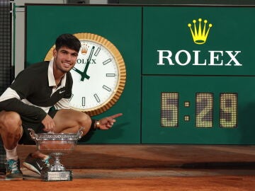 Alcaraz posa con la Copa de los Mosqueteros junto al reloj que marca el tiempo que duró la final de Roland Garros