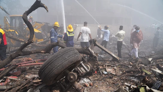 Unas personas apagan el fuego junto a los escombros en el lugar donde se estrelló este jueves un avión de Air India Unas personas apagan el fuego junto a los escombros en el lugar donde se estrelló este jueves un avión de Air India