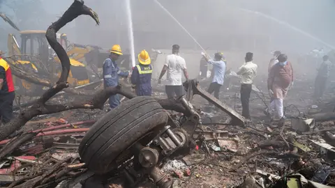 Unas personas apagan el fuego junto a los escombros en el lugar donde se estrelló este jueves un avión de Air India Unas personas apagan el fuego junto a los escombros en el lugar donde se estrelló este jueves un avión de Air India