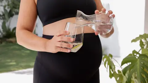 Una mujer embarazada bebiendo agua Una mujer embarazada bebiendo agua