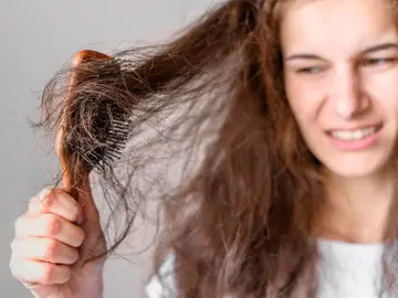 Mujer peinando un pelo con frizz Mujer peinando un pelo con frizz