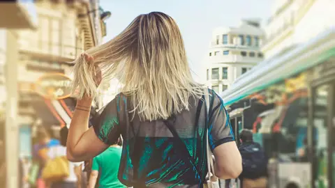 Mujer se toca el cabello paseando por la ciudad Mujer se toca el cabello paseando por la ciudad