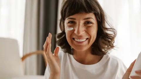 Mujer poniéndose crema en la cara Mujer poniéndose crema en la cara