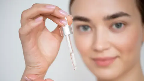 Mujer sujetando un cosmético Mujer sujetando un cosmético