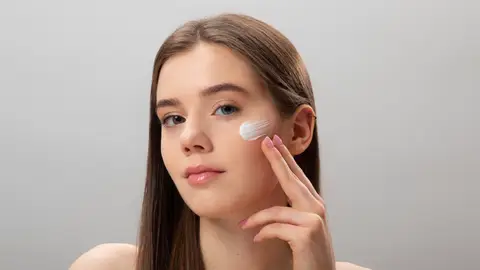 Mujer poniéndose crema en la cara Mujer poniéndose crema en la cara