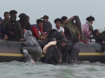 Migrantes intentan subirse a una lancha para cruzar el canal de la Mancha