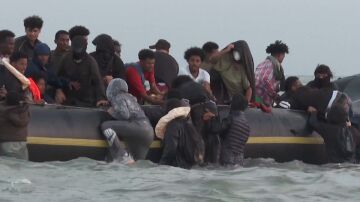 Migrantes intentan subirse a una lancha para cruzar el canal de la Mancha