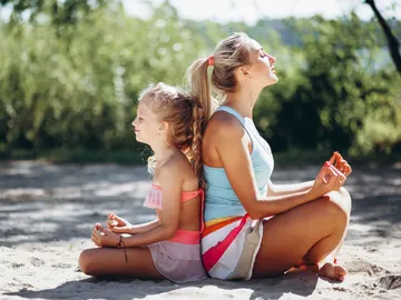 Madre e hija practicando yoga y meditación en la playa Madre e hija practicando yoga y meditación en la playa