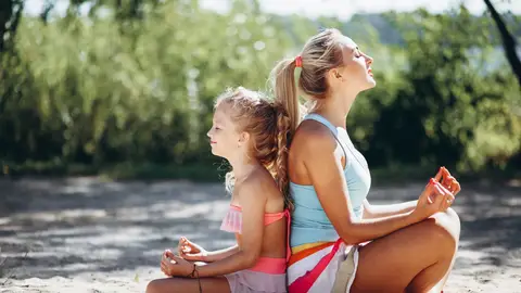 Madre e hija practicando yoga y meditación en la playa Madre e hija practicando yoga y meditación en la playa
