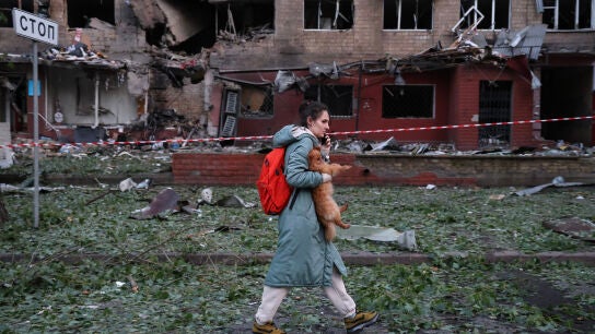 Una mujer con un perro peque&ntilde;o es evacuada de un edificio residencial de cinco pisos en el distrito de Solomyanskyi, gravemente da&ntilde;ado por un ataque a&eacute;reo ruso el 4 de julio de 2025 en Kiev, Ucrania.