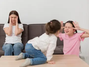 Madre saturada frente a sus hijas peleándose Madre saturada frente a sus hijas peleándose