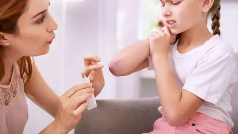 Una madre desinfecta una herida del codo a su hija Una madre desinfecta una herida del codo a su hija