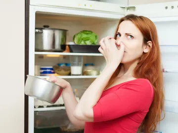 Una mujer se tapa la nariz ante el mal olor de la nevera Una mujer se tapa la nariz ante el mal olor de la nevera