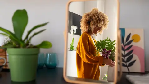 Una mujer ordenando sus plantas en casa Una mujer ordenando sus plantas en casa