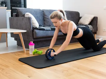 Mujer entrenando con un rodillo abdominal Mujer entrenando con un rodillo abdominal