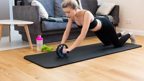 Mujer entrenando con un rodillo abdominal Mujer entrenando con un rodillo abdominal