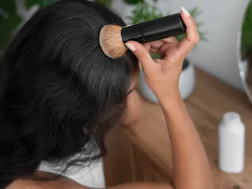 Mujer aplicándose la brocha solar en el cabello Mujer aplicándose la brocha solar en el cabello