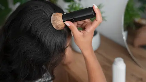 Mujer aplicándose la brocha solar en el cabello Mujer aplicándose la brocha solar en el cabello