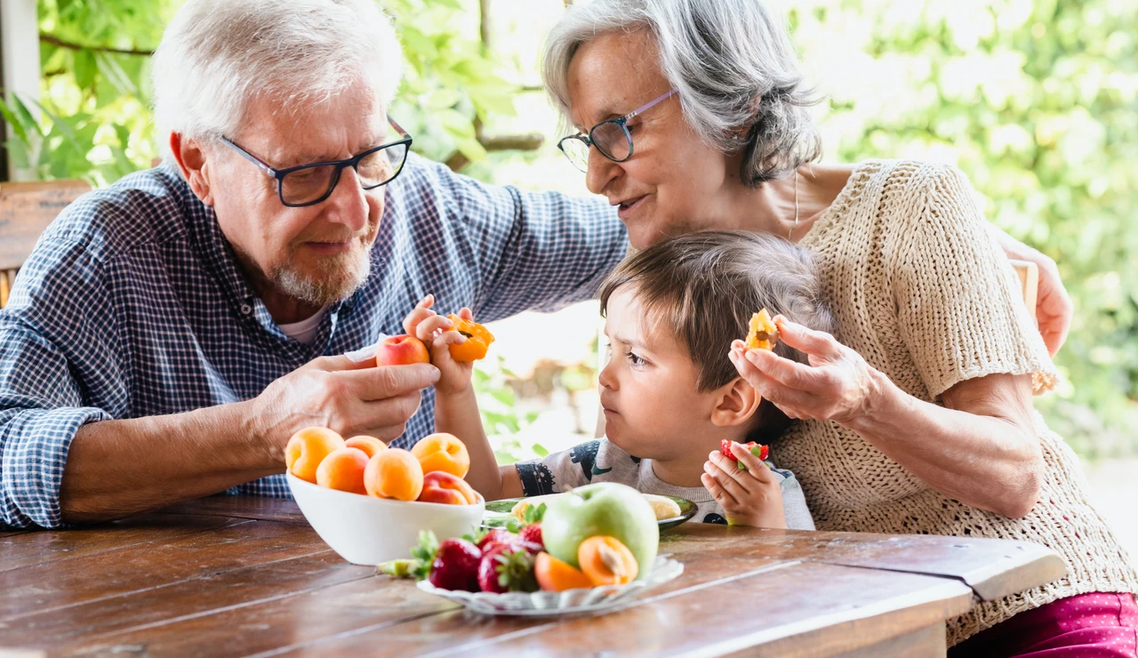 Unos abuelos comiendo fruta junto a su nieta