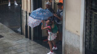Varias personas se protegen de la lluvia