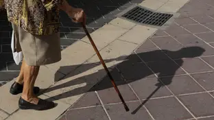 Imagen de un bastón y los pies de una anciana. Imagen de un bastón y los pies de una anciana.