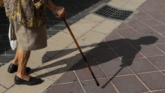 Imagen de un bastón y los pies de una anciana. Imagen de un bastón y los pies de una anciana.