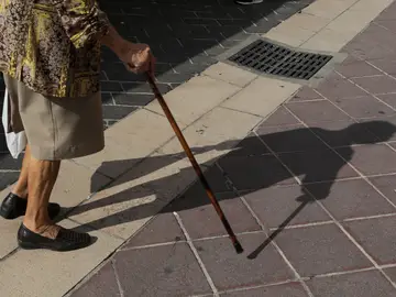 Imagen de un bastón y los pies de una anciana. Imagen de un bastón y los pies de una anciana.