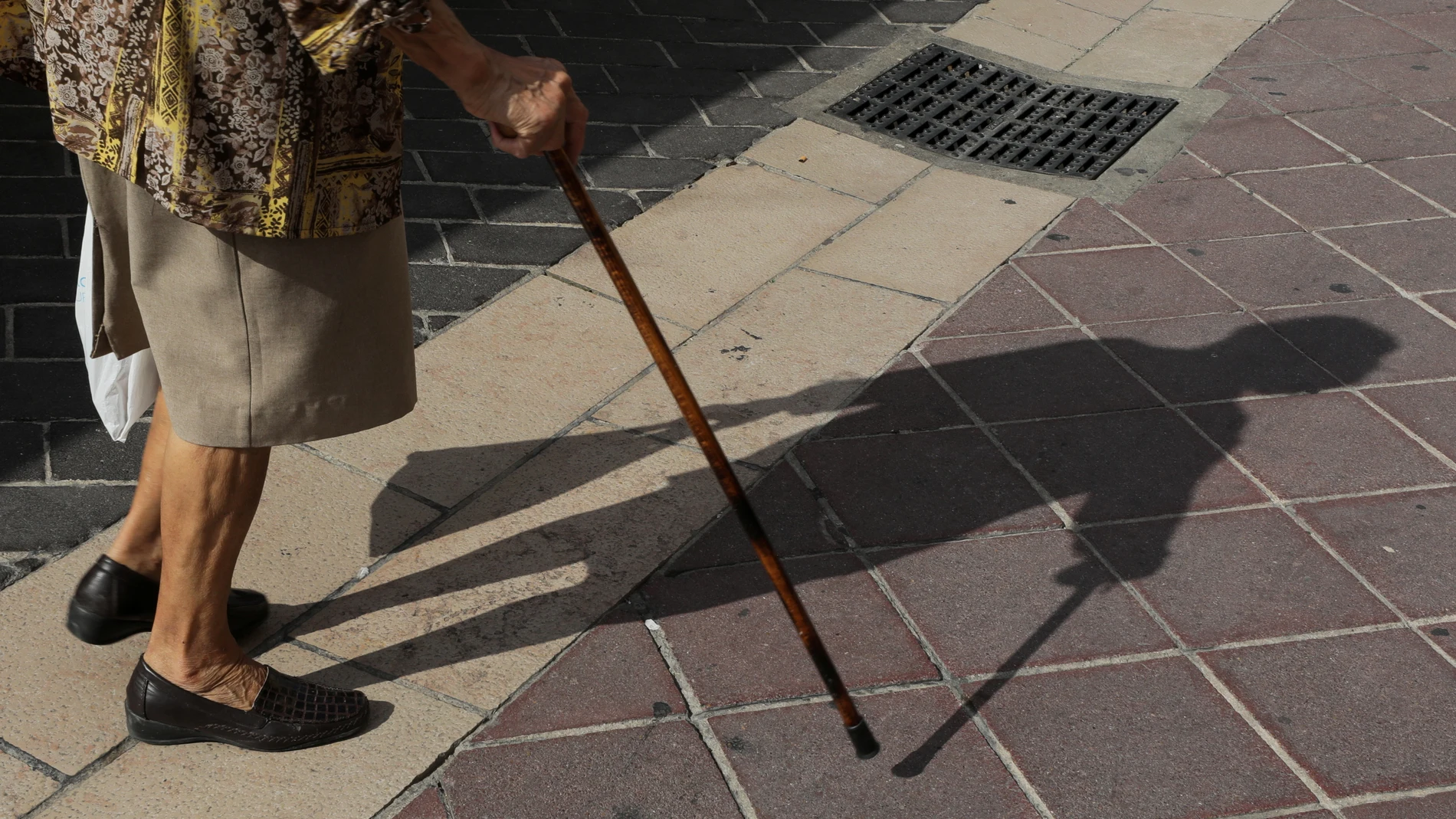 Imagen de un bastón y los pies de una anciana. Imagen de un bastón y los pies de una anciana.