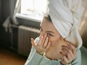 Mujer joven cuidándose el rostro Mujer joven cuidándose el rostro