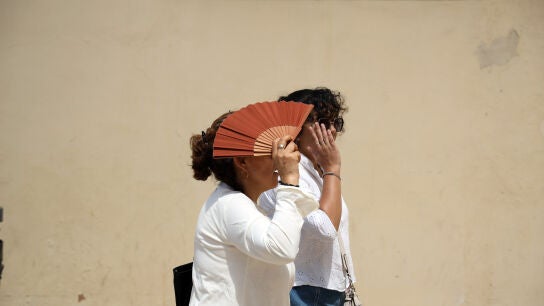 Varias personas se protegen del sol en una calle de M&aacute;laga. 