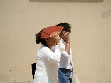 Varias personas se protegen del sol en una calle de Málaga. 