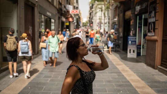 Una mujer bebe agua de una botella en una calle c&eacute;ntrica durante una ola de calor en la ciudad de Santa Cruz de Tenerife, Islas Canarias.