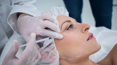 Mujer realizándose un retoque estético Mujer realizándose un retoque estético