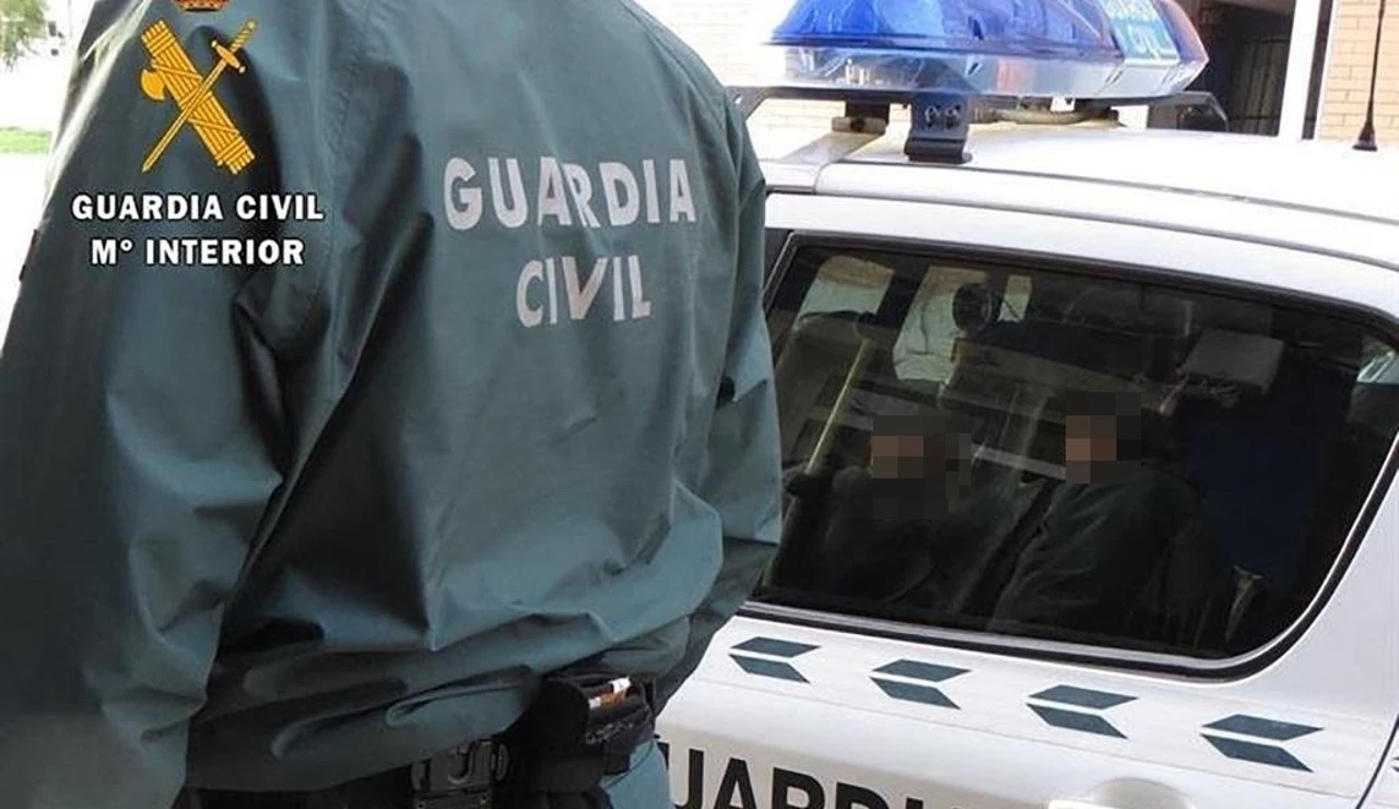 Agente de la Guardia Civil junto a un coche patrulla.