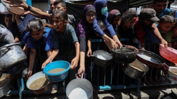 Displaced Palestinians wait to receive free food at a distribution center in Gaza City