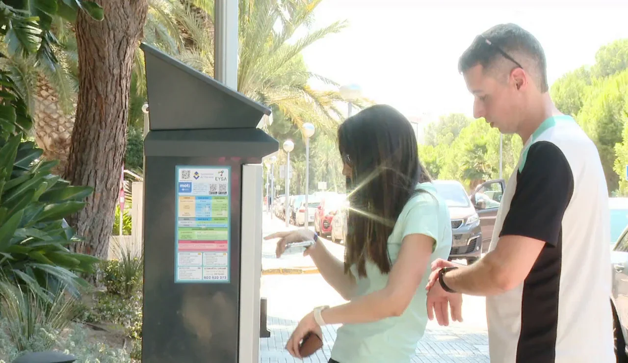 Imagen de dos chicos usando un parkímetro.