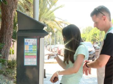 Imagen de dos chicos usando un parkímetro. 