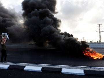 Un manifestante sostiene una foto de un rehén israelí mientras los manifestantes bloquean una carretera