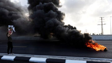 Un manifestante sostiene una foto de un rehén israelí mientras los manifestantes bloquean una carretera