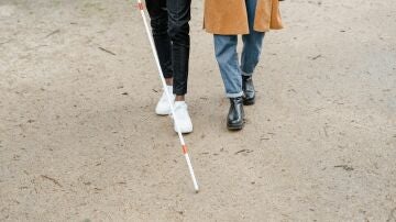 Imagen de una persona ciega caminando con un bastón. 