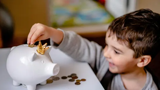 Un niño mete dinero en su hucha Un niño mete dinero en su hucha