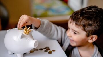 Un niño mete dinero en su hucha
