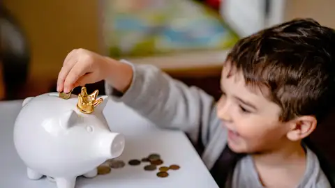 Un niño mete dinero en su hucha Un niño mete dinero en su hucha