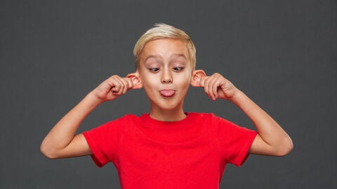 Niño sacando la lengua y estirándose de las orejas