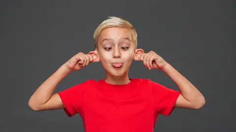 Niño sacando la lengua y estirándose de las orejas Niño sacando la lengua y estirándose de las orejas