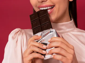 Una mujer comiendo una tableta de chocolate Una mujer comiendo una tableta de chocolate