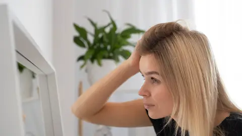 Mujer mirándose el pelo en el espejo Mujer mirándose el pelo en el espejo