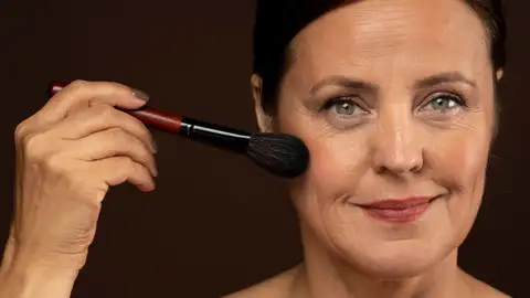Mujer aplicándose colorete Mujer aplicándose colorete