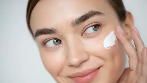 Mujer poniéndose un cosmético Mujer poniéndose un cosmético