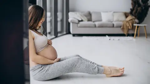 Mujer embarazada mirándose los pies Mujer embarazada mirándose los pies
